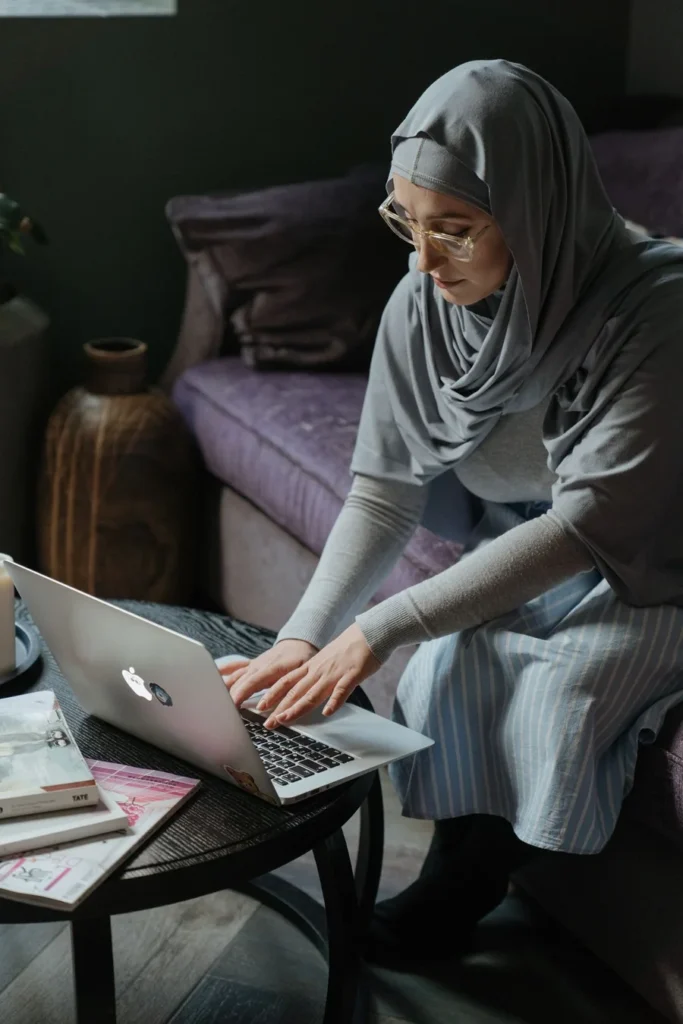 Muslim woman in hijab attending a live online Quran class on a laptop at home
